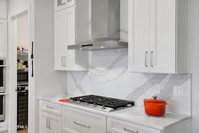 181 Lamego Ln, Saint Augustine, FL 32095 - kitchen with wall chimney range hood, stainless steel gas stovetop, white cabinetry, and decorative backsplash