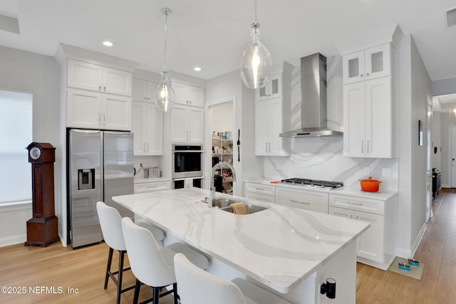 181 Lamego Ln, Saint Augustine, FL 32095 - kitchen featuring stainless steel appliances, a sink, wall chimney exhaust hood, light wood-type flooring, and white cabinetry