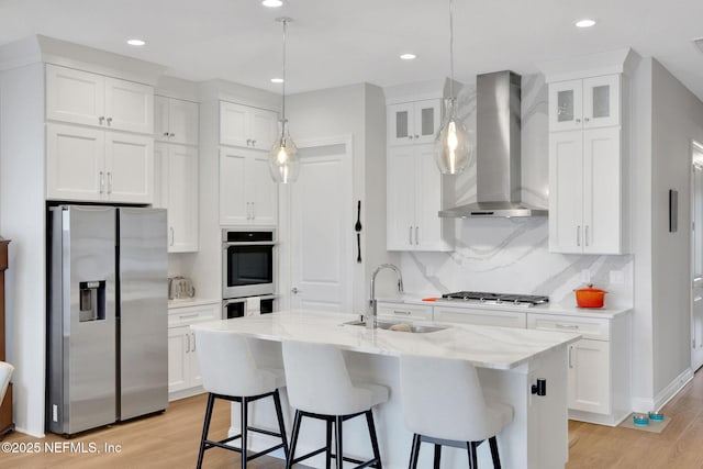 181 Lamego Ln, Saint Augustine, FL 32095 - kitchen featuring stainless steel appliances, wall chimney exhaust hood, a sink, light wood-type flooring, and white cabinets