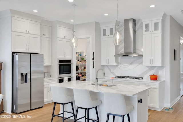 181 Lamego Ln, Saint Augustine, FL 32095 - kitchen with appliances with stainless steel finishes, wall chimney range hood, a sink, light wood-style flooring, and white cabinetry