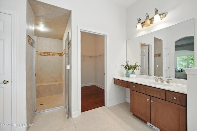 5279 Cattle Crossing Way, Jacksonville, FL 32226 - bathroom featuring baseboards, tiled shower, tile patterned floors, vanity, and a walk in closet