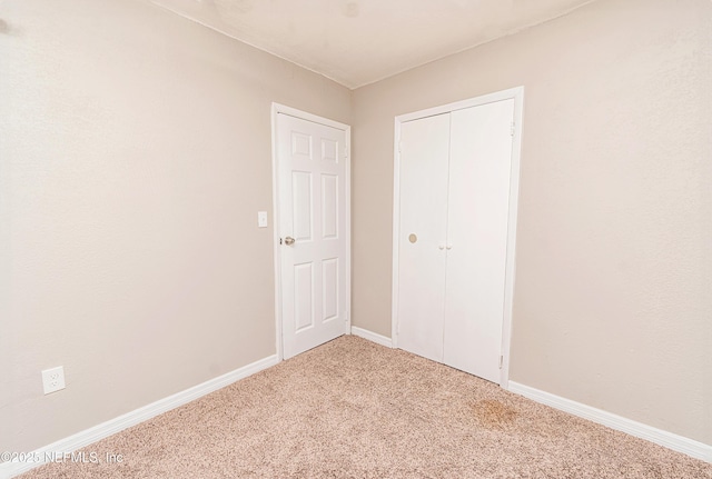 unfurnished bedroom featuring carpet, a closet, and baseboards