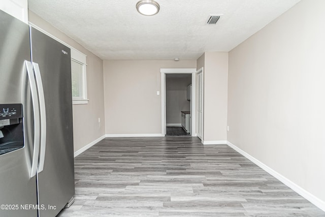 interior space featuring baseboards, a textured ceiling, and wood finished floors