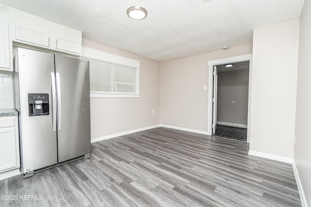 kitchen with light wood-style floors, baseboards, and stainless steel refrigerator with ice dispenser