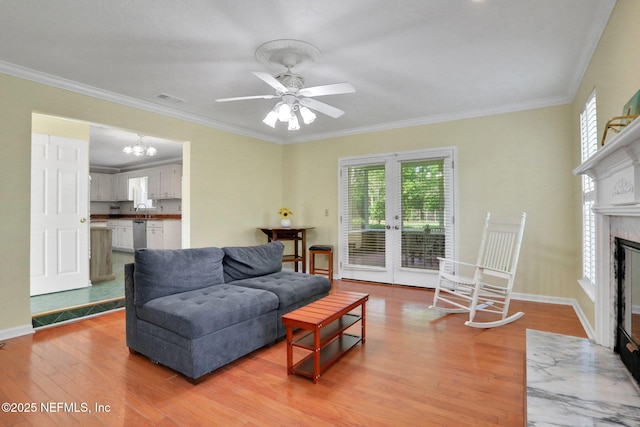 12602 Wimica Ln, Jacksonville, FL 32218 - living room featuring light wood-style flooring, ornamental molding, ceiling fan, a high end fireplace, and a chandelier