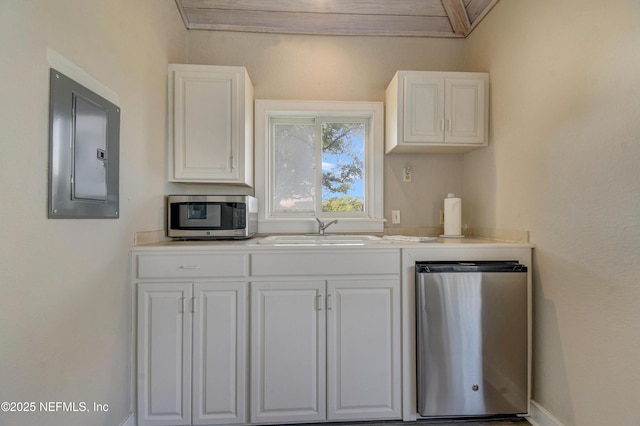 kitchen featuring stainless steel microwave, electric panel, a sink, and white cabinetry