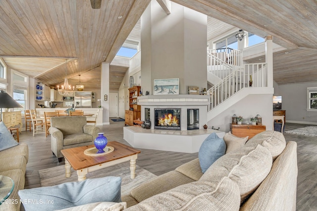living room with a chandelier, baseboards, wood ceiling, stairway, and high vaulted ceiling