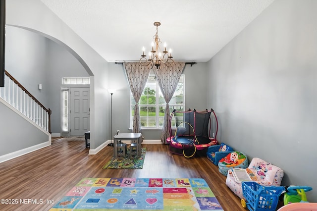 game room with a chandelier, arched walkways, wood finished floors, and baseboards