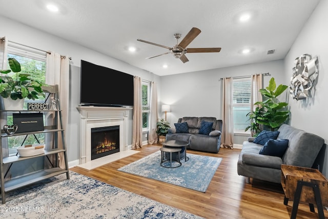 living area with a ceiling fan, plenty of natural light, wood finished floors, and recessed lighting