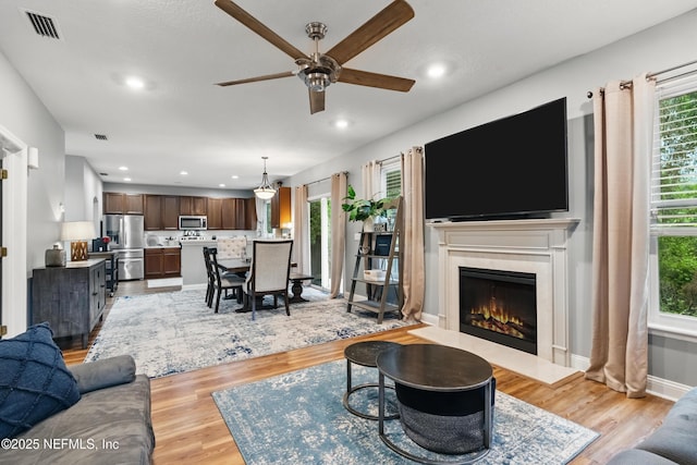 living area with ceiling fan, healthy amount of natural light, light wood-style floors, and recessed lighting