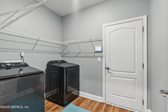 laundry area featuring washing machine and dryer, light wood finished floors, and baseboards