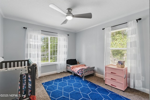 carpeted bedroom featuring crown molding, multiple windows, baseboards, and a ceiling fan