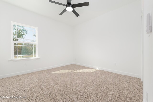 carpeted empty room featuring baseboards and a ceiling fan