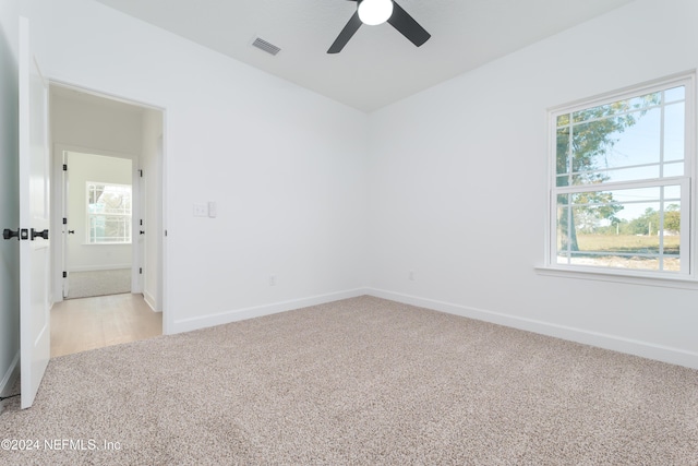 spare room with light colored carpet, ceiling fan, baseboards, and healthy amount of natural light