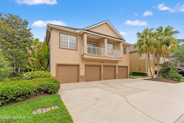 townhome / multi-family property with stucco siding, concrete driveway, a garage, and a balcony