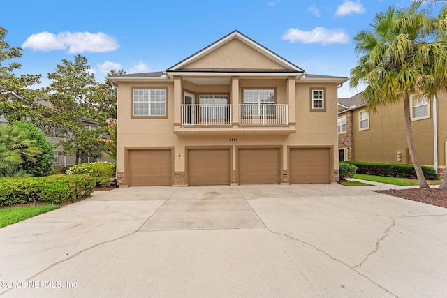 view of front of home featuring a balcony, stucco siding, concrete driveway, and an attached garage