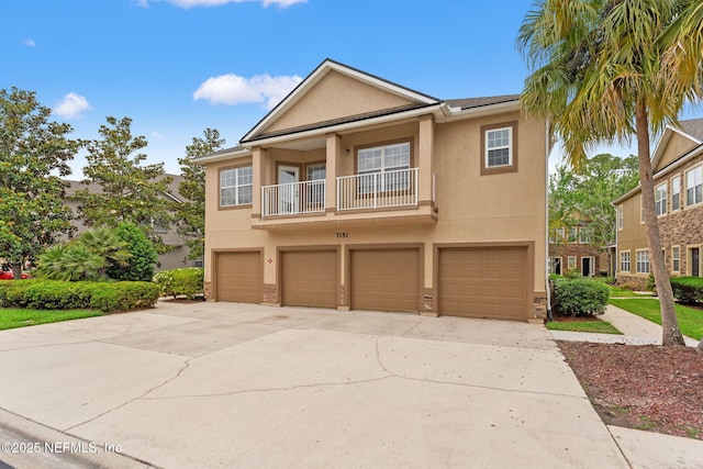 townhome / multi-family property featuring driveway, a balcony, stucco siding, and an attached garage