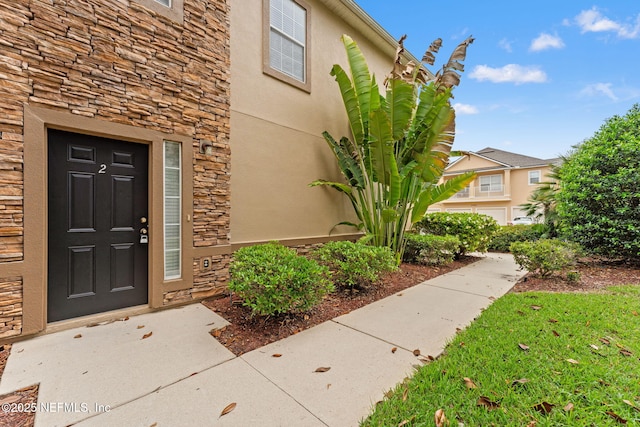 entrance to property with stone siding and stucco siding