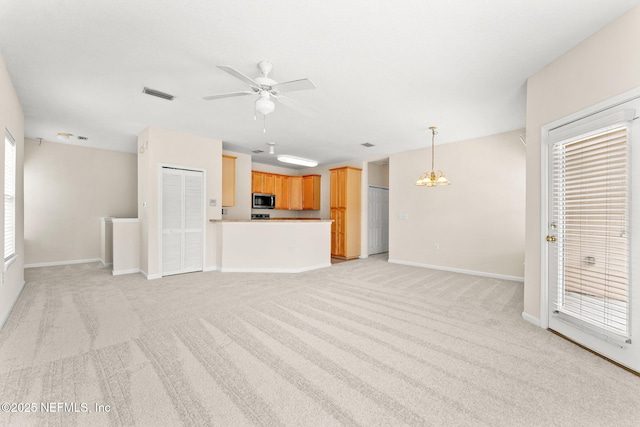 unfurnished living room with a ceiling fan, light carpet, baseboards, and a chandelier
