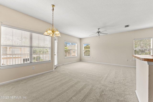 empty room featuring ceiling fan, a chandelier, baseboards, carpet flooring, and a textured ceiling