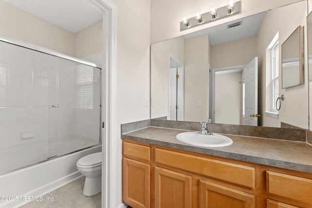 bathroom with toilet, tile patterned flooring, vanity, and enclosed tub / shower combo