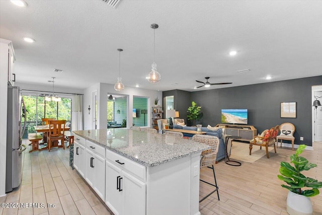 169 Rivercliff Trl, Saint Augustine, FL 32092 - kitchen with freestanding refrigerator, ceiling fan, light wood finished floors, white cabinets, and light stone counters