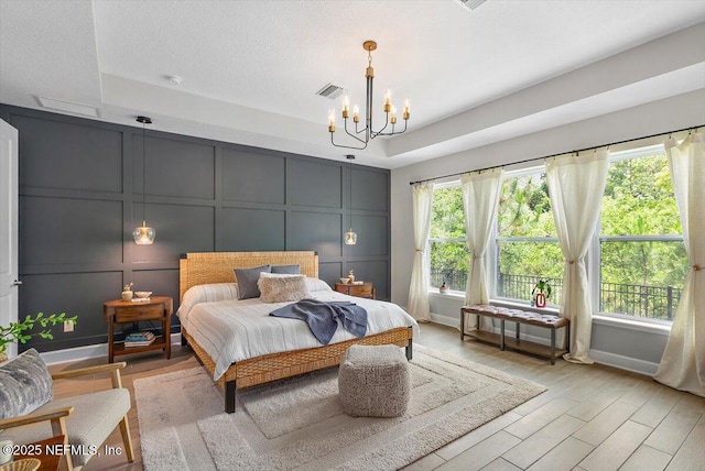 169 Rivercliff Trl, Saint Augustine, FL 32092 - bedroom featuring a decorative wall, a chandelier, a raised ceiling, and light wood-style floors