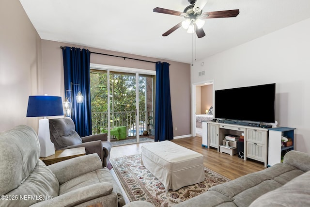 living room featuring a ceiling fan, baseboards, visible vents, and wood finished floors
