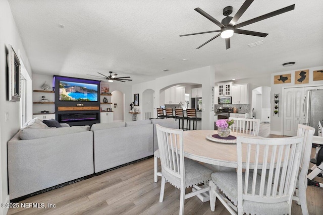 11698 Donato Dr, Jacksonville, FL 32226 - dining space with ceiling fan, a textured ceiling, arched walkways, and light wood-type flooring