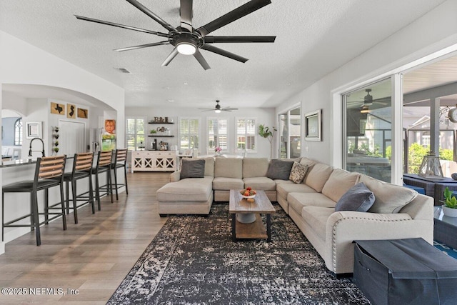 11698 Donato Dr, Jacksonville, FL 32226 - living area featuring a ceiling fan, wood finished floors, a textured ceiling, and arched walkways