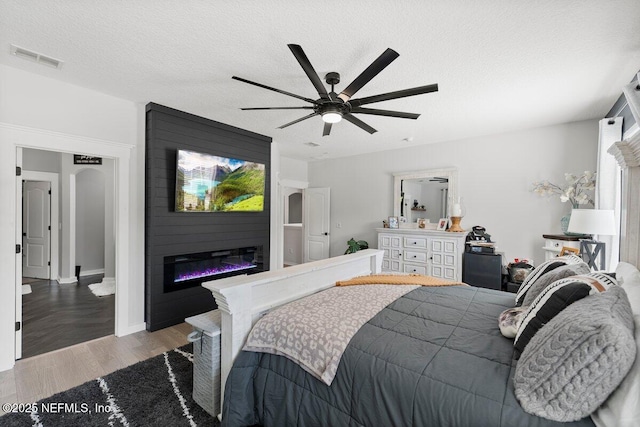 11698 Donato Dr, Jacksonville, FL 32226 - bedroom with a fireplace, wood finished floors, a ceiling fan, and a textured ceiling