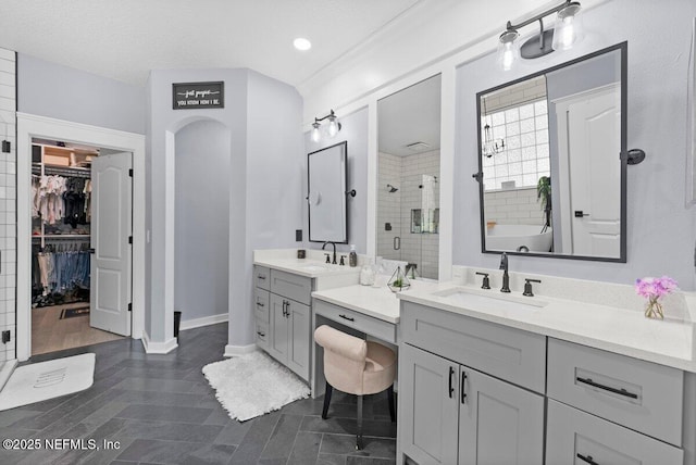 11698 Donato Dr, Jacksonville, FL 32226 - bathroom with a stall shower, two vanities, a walk in closet, baseboards, and recessed lighting