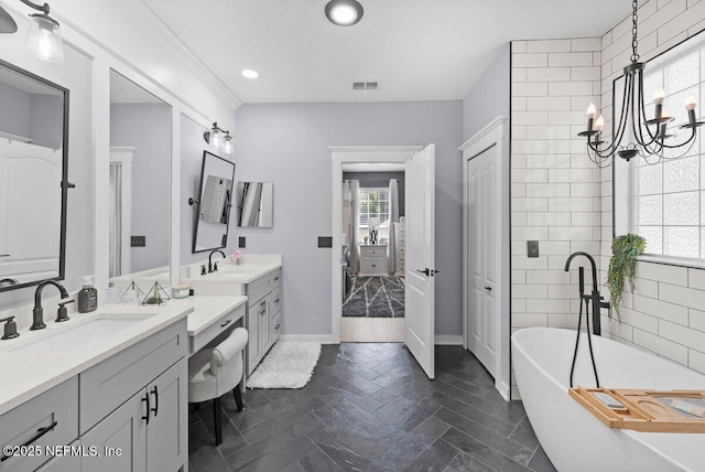 11698 Donato Dr, Jacksonville, FL 32226 - bathroom featuring healthy amount of natural light, a freestanding tub, two vanities, a chandelier, and recessed lighting