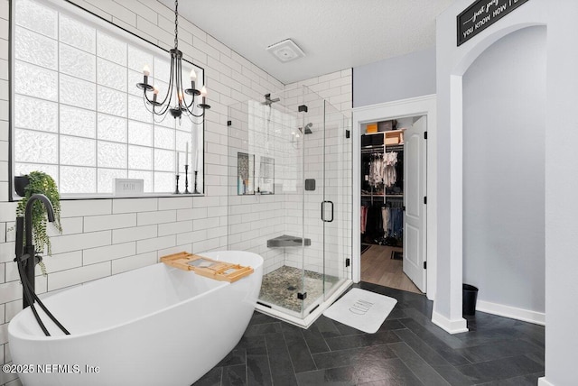 11698 Donato Dr, Jacksonville, FL 32226 - bathroom featuring a stall shower, a walk in closet, a freestanding bath, tile walls, and a chandelier