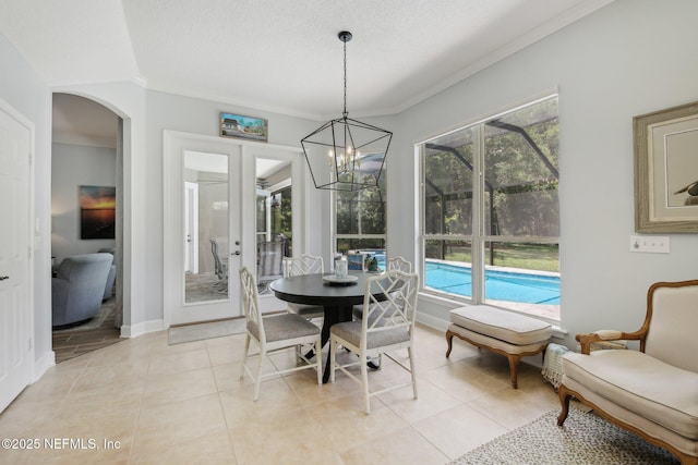 dining space featuring plenty of natural light, light tile patterned flooring, arched walkways, ornamental molding, and a chandelier