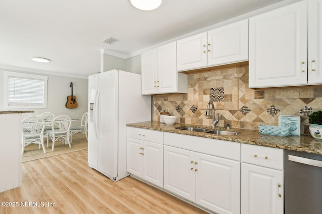 2902 W 5th St, Fernandina Beach, FL 32034 - kitchen featuring a sink, dishwasher, decorative backsplash, white refrigerator with ice dispenser, and white cabinetry