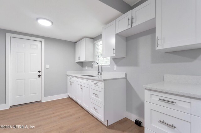 3321 Deason Ave, Jacksonville, FL 32254 - kitchen with a sink, baseboards, white cabinetry, and light wood finished floors
