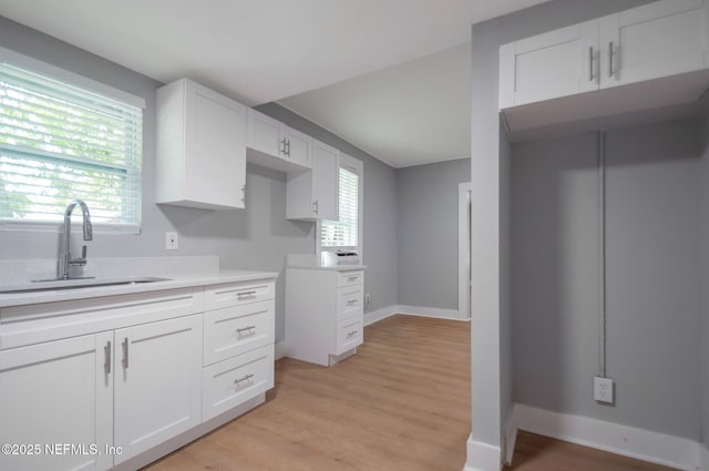 3321 Deason Ave, Jacksonville, FL 32254 - kitchen featuring a sink, light wood-style flooring, white cabinets, and light countertops