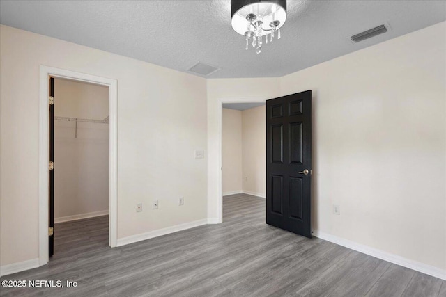 3357 Pegaso Ave, New Smyrna Beach, FL 32168 - unfurnished bedroom with wood finished floors, a spacious closet, baseboards, a closet, and a textured ceiling