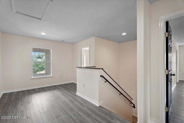 3357 Pegaso Ave, New Smyrna Beach, FL 32168 - unfurnished room with a textured ceiling, wood finished floors, baseboards, recessed lighting, and attic access