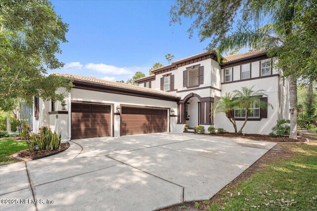 3357 Pegaso Ave, New Smyrna Beach, FL 32168 - mediterranean / spanish-style home with a tile roof, an attached garage, concrete driveway, and stucco siding