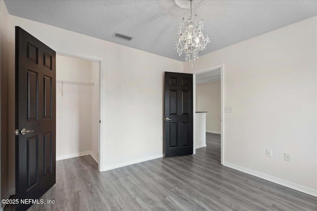 3357 Pegaso Ave, New Smyrna Beach, FL 32168 - unfurnished bedroom featuring a chandelier, wood finished floors, baseboards, a closet, and a textured ceiling