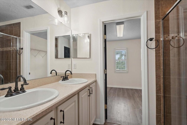 3357 Pegaso Ave, New Smyrna Beach, FL 32168 - bathroom with a textured ceiling, a stall shower, wood finished floors, and double vanity