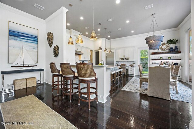 231 N Roscoe Blvd, Ponte Vedra Beach, FL 32082 - kitchen featuring crown molding, built in refrigerator, a breakfast bar area, white cabinetry, and dark wood-style floors
