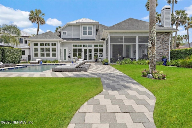 231 N Roscoe Blvd, Ponte Vedra Beach, FL 32082 - back of house with a sunroom, a chimney, an outdoor pool, a lawn, and a patio
