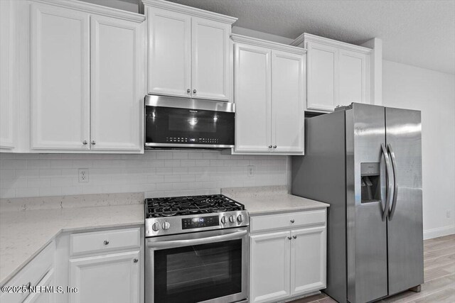 kitchen featuring stainless steel appliances, white cabinetry, and backsplash
