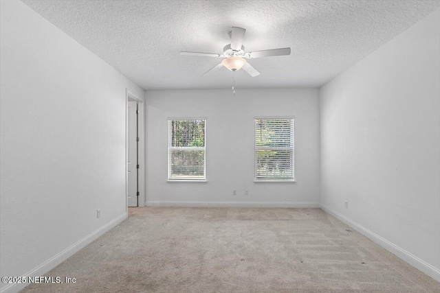 carpeted spare room featuring a ceiling fan, baseboards, and a textured ceiling