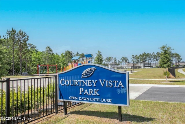 community sign with fence and a lawn