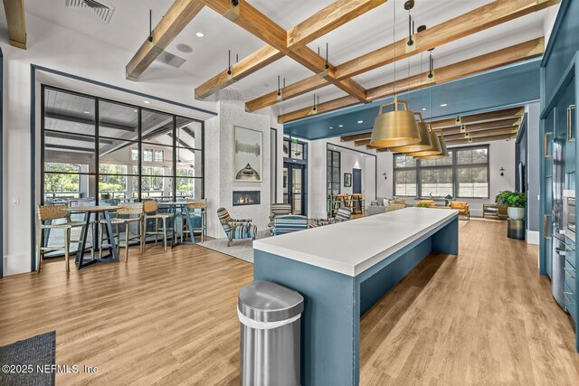 75556 Canterwood Dr, Yulee, FL 32097 - kitchen with beamed ceiling, light wood-type flooring, blue cabinets, hanging light fixtures, and a kitchen island