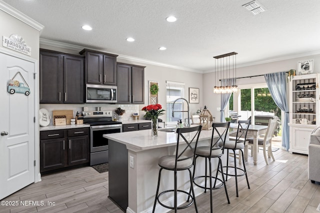 2565 Cold Stream Ln, Green Cove Springs, FL 32043 - kitchen featuring appliances with stainless steel finishes, a sink, light wood-style flooring, a kitchen bar, and crown molding